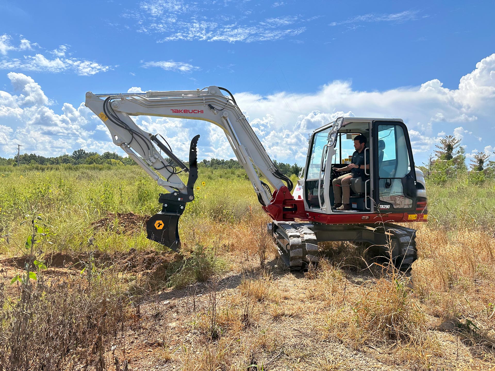 A mini excavator digging with a bucket and a thumb attachment.