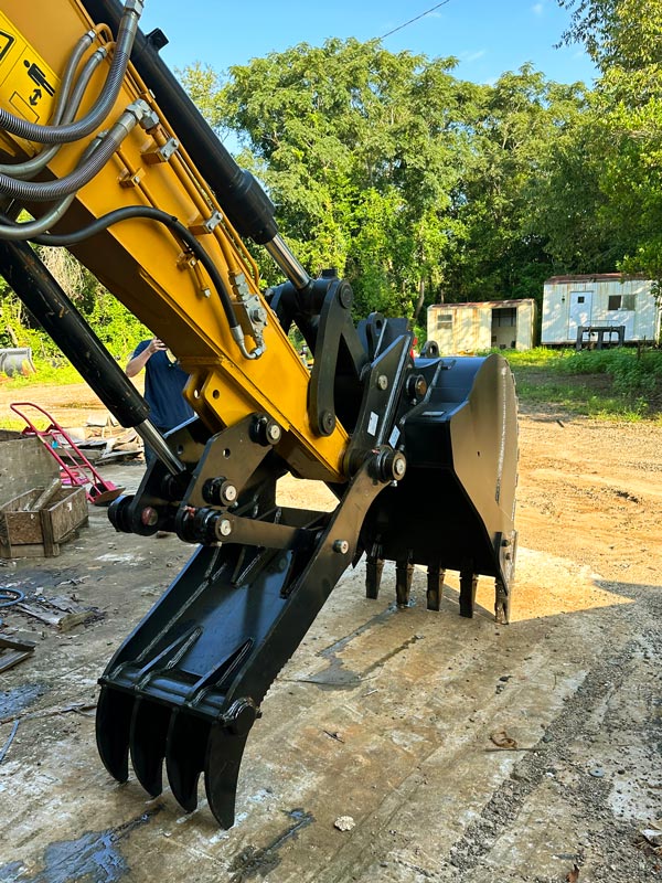 An excavator with a bucket and a thumb attachment.