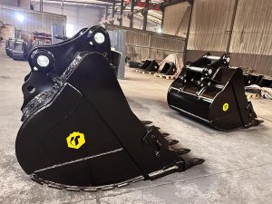 A warehouse with about a dozen heavy duty excavator buckets on pallets.